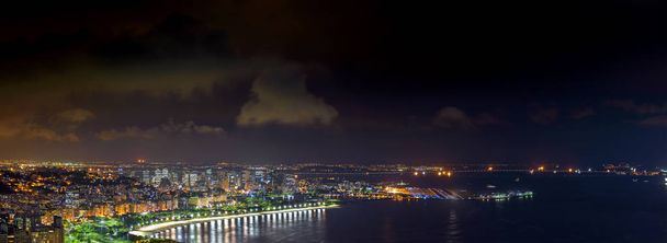 Panoramisch beeld van Rio de Janeiro van bovenaf gezien bij nacht met lichten, heuvels, straten, Gaunabara bay, Rio-Niteroi brug en Santos Dumont luchthaven - Foto, afbeelding