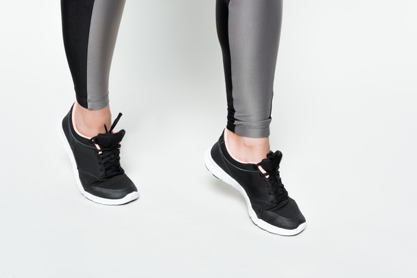 Kadın bacaklarını açıp görünümünü yakın çekim spor ayakkabıları üzerinde beyaz izole - Fotoğraf, Görsel