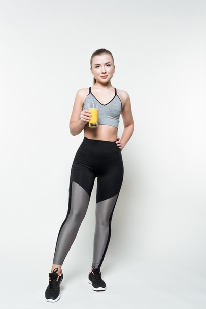 Blonde woman in sport clothes holding glass with juice isolated on white - Foto, Bild