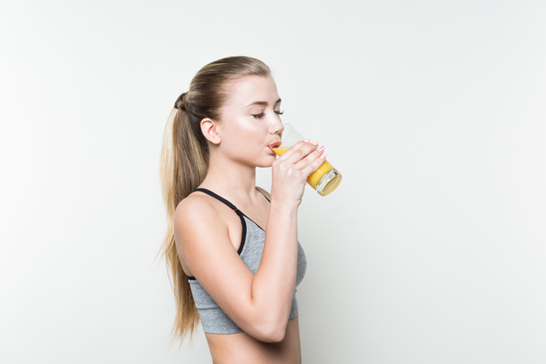 Fit girl drinking juice from glass isolated on white - Photo, image