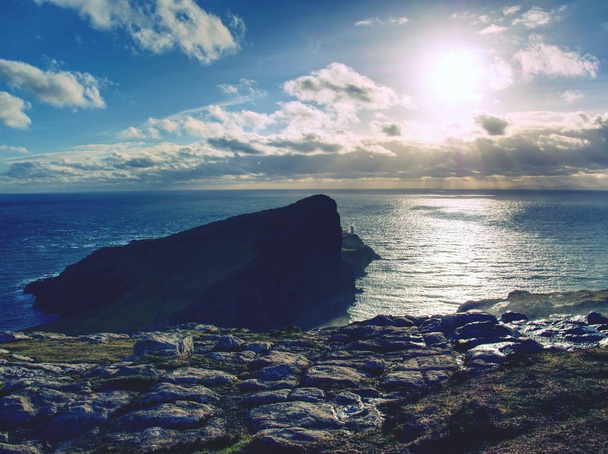 Neist Point lighthouse na skalnatém útesu nad zvlněné moře. Modré večerní moře a útesy, - Fotografie, Obrázek