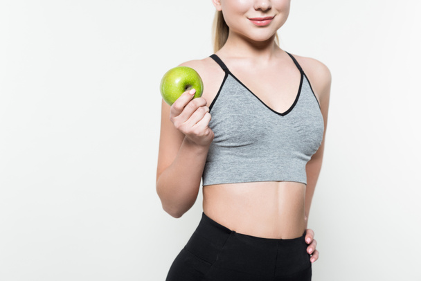 Cropped view of sportive girl holding apple isolated on white - Fotó, kép