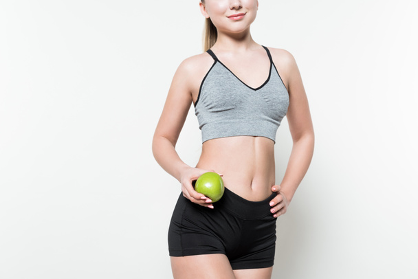 Blondynka w trzyma jabłko na białym tle odzież sportową - Zdjęcie, obraz