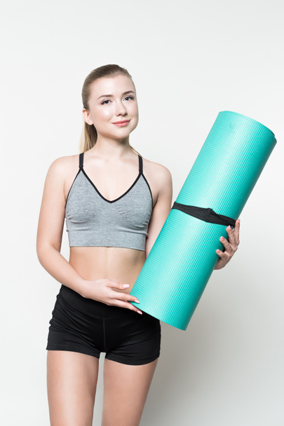 Attractive sportive woman holding yoga mat isolated on white - 写真・画像