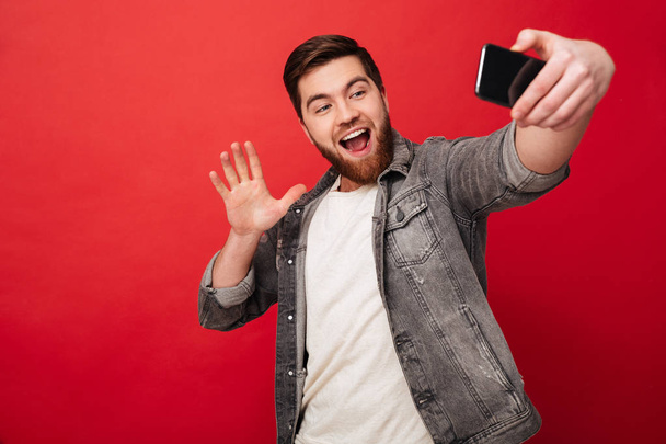 Happy man making selfie on smartphone and waving at camera - Valokuva, kuva