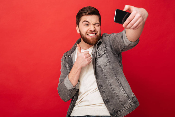 Funny man making selfie on smartphone and showing thumb up - Fotó, kép