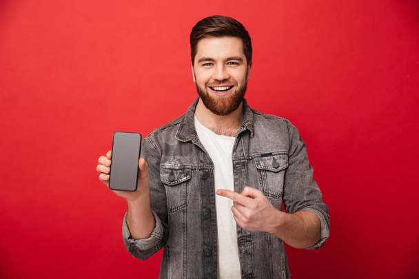 Image of young brunette man pointing finger on smartphone and sm - Zdjęcie, obraz