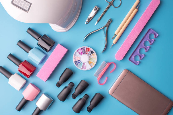 Joukko kosmeettisia työkaluja manikyyri ja pedikyyri sinisellä pohjalla. Geelin kiillotus, kynsiviilat ja leikkurit, ylhäältä katsottuna
 - Valokuva, kuva