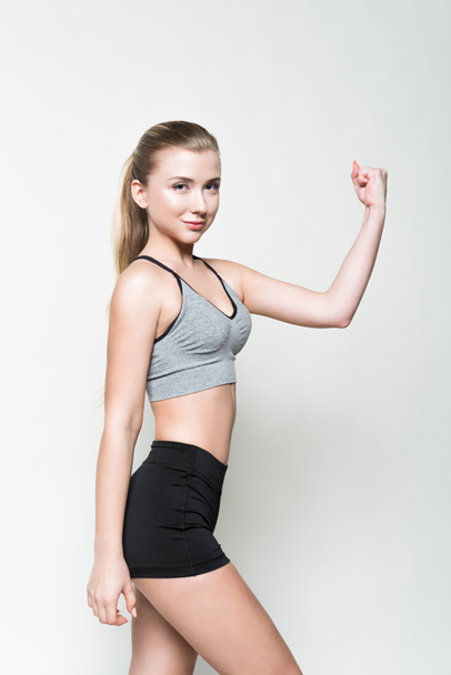 Young girl in sports clothes showing biceps isolated on white - Фото, зображення