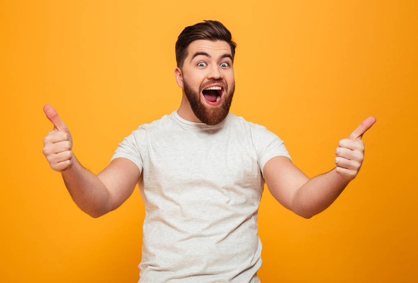 Portrait of a happy bearded man showing thumbs up - Фото, изображение