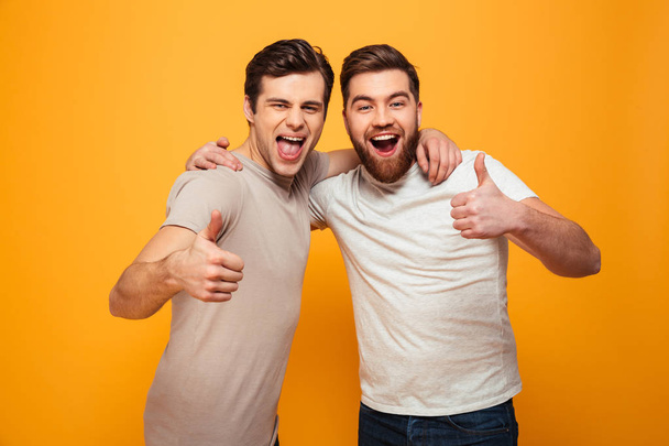 Portrait of a two happy young men showing thumbs up - Fotó, kép