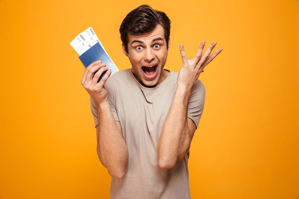 Portrait of a happy young man holding passport - 写真・画像