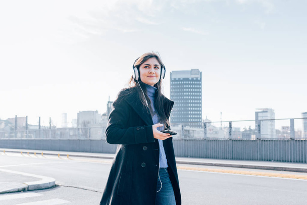 Młoda kobieta spaceru w miasto Powrót światła słuchania słuchawki muzyki ze smartfona  - Zdjęcie, obraz