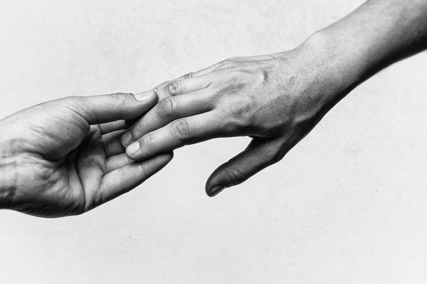 Emotional, black and white photo of two hands at the moment of farewell. The concept of breaking relations. - Photo, Image