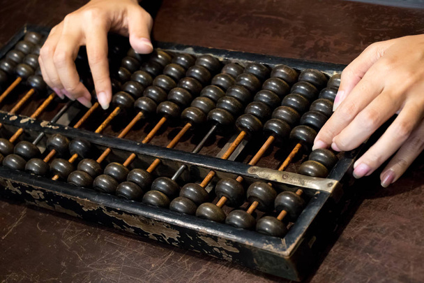 Gesloten op van de zakelijke vrouw hand die berekenen met hout abacus (traditionele chinese rekenmachine) - Foto, afbeelding
