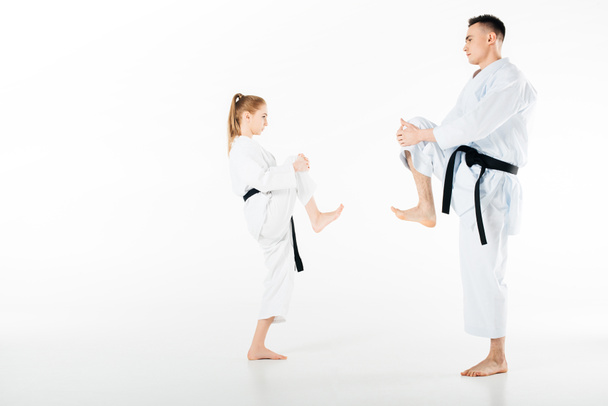 Seitenansicht von Karate-Kämpfern, die die Beine isoliert auf weiß strecken - Foto, Bild