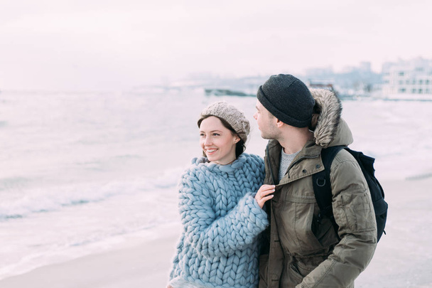 coppia sorridente che abbraccia e cammina sulla riva del mare invernale
 - Foto, immagini