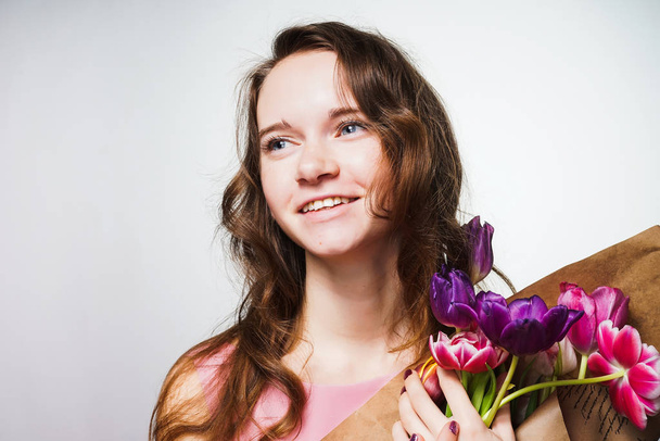smiling young woman holding a big bouquet of fragrant flowers, smiling, celebrating a world women's day - Foto, Imagen