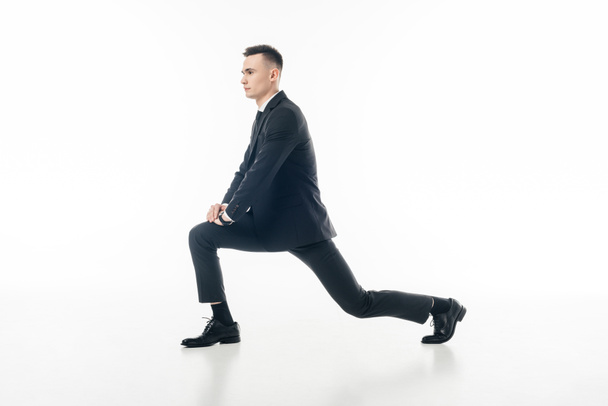 businessman stretching legs in suit isolated on white - 写真・画像