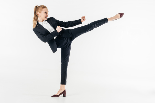 businesswoman performing karate kick in suit and high heels isolated on white - Fotografie, Obrázek