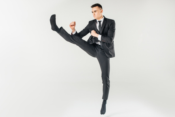 businessman jumping and performing kick in suit isolated on white - Photo, image
