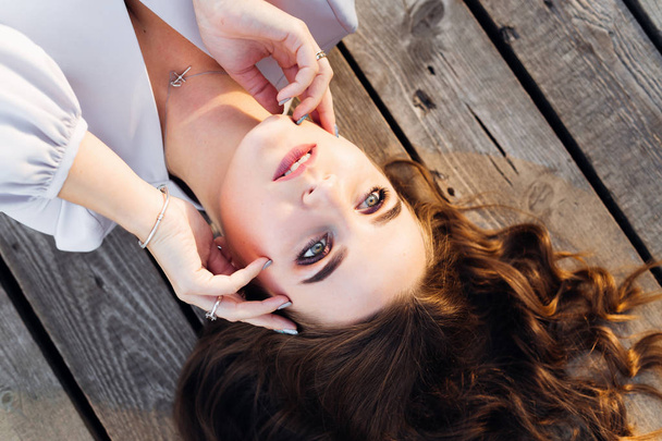 beautiful eyes in a girl who lying on a wooden surface and holding hands near her face - Fotoğraf, Görsel