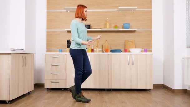 Woman in casual clothes dances in the kitchen - Séquence, vidéo