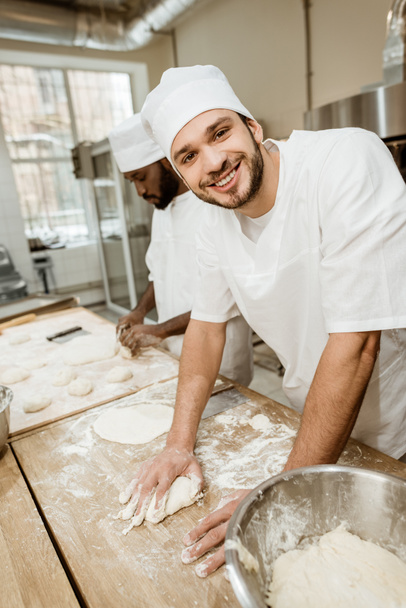 szczęśliwy przystojny piekarzy, wyrabiania ciasta razem w pieczeniu produkcji - Zdjęcie, obraz