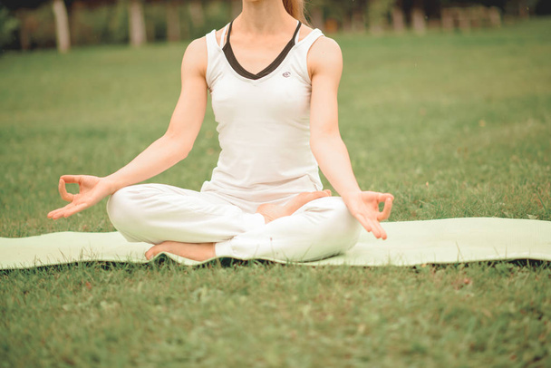 a woman does yoga and meditates on the green grass - Φωτογραφία, εικόνα