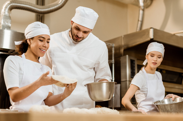 young multiethnic team of bakers working together at baking manufacture - Фото, зображення