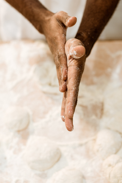 Colpo ritagliato di panettiere afroamericano che prepara l'impasto per la pasticceria e copre le mani nella farina
 - Foto, immagini