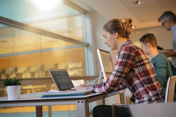 Студентка, сидящая в классе и работающая на ноутбуке
 - Фото, изображение