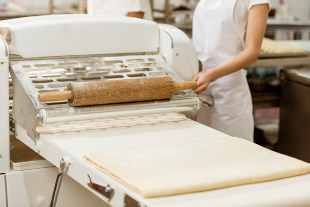 tiro recortado de panadero hembra con la lista de masa cruda en la fabricación de hornear
 - Foto, Imagen