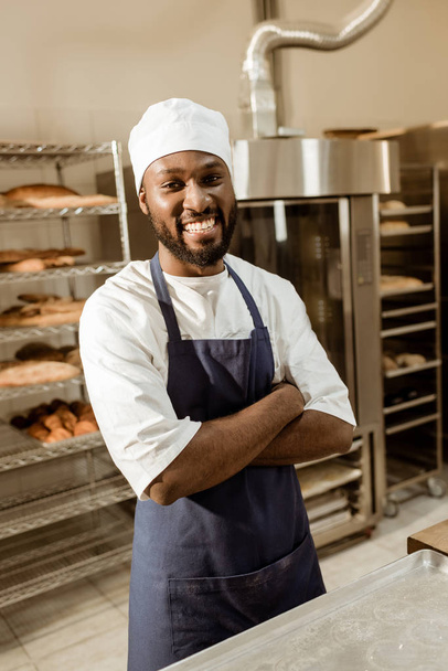 souriant boulanger afro-américain avec les bras croisés sur la fabrication de cuisson
 - Photo, image