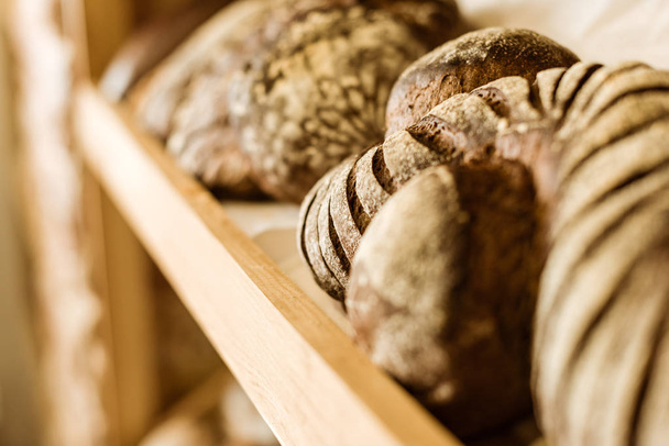 Close-up shot van verschillende landelijke brood op de plank bij de winkel gebak - Foto, afbeelding