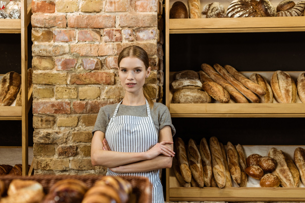 hermoso panadero joven con brazos cruzados de pie en la pastelería
 - Foto, Imagen