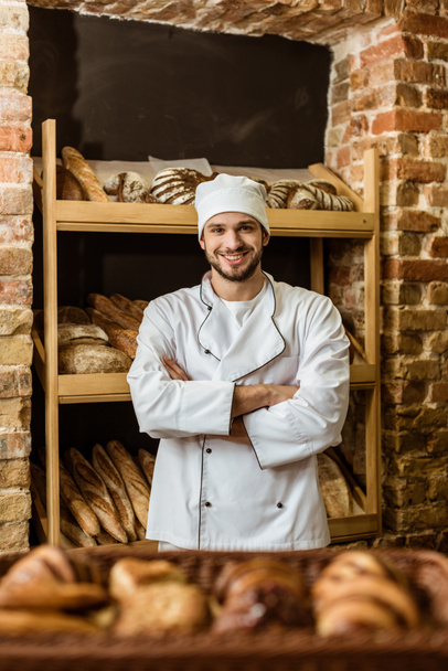 panadero sonriente guapo con brazos cruzados de pie en la pastelería
 - Foto, Imagen