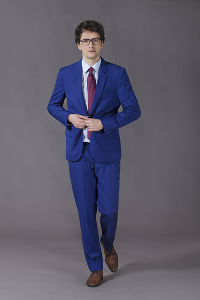 Young kinky man making step and unbuttoning his blue jacket - Photo, image