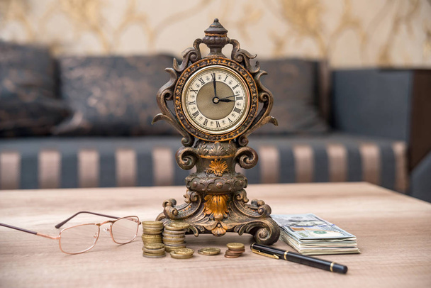 viejo reloj con cuaderno, pluma y dinero en la mesa
 - Foto, Imagen