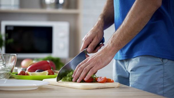 Ο άνθρωπος κοπή ντομάτες και το μαρούλι προετοιμασία φρέσκια σαλάτα λαχανικών, υγιεινή διατροφή - Φωτογραφία, εικόνα