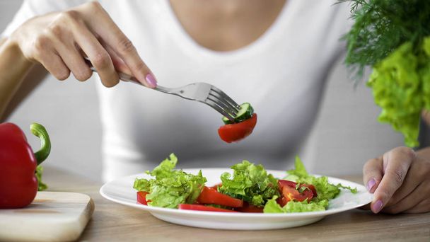 Γυναίκα τρώει σαλάτα λαχανικών, παρατηρώντας διατροφή και καταμέτρηση θερμίδων, wellness - Φωτογραφία, εικόνα