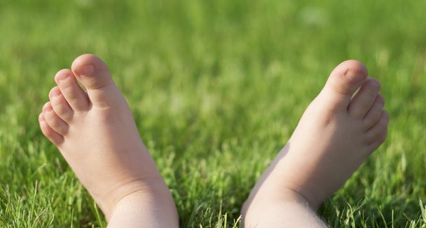 Descalço da criança na grama verde
 - Foto, Imagem