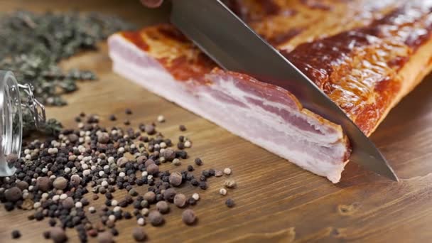 Chef corta trozos de tocino ahumado con un cuchillo afilado en la tabla de madera, cocina carne, comidas con productos cárnicos, cocina cerdo
 - Metraje, vídeo