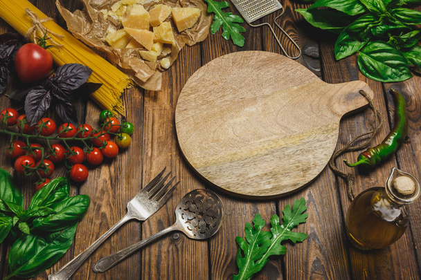 Tło makaron. Suche spaghetti z serem, warzywa i zioła na drewnianym stole. Widok z góry - Zdjęcie, obraz