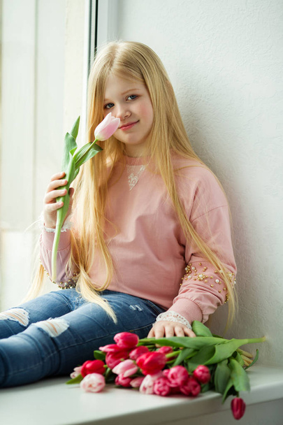 Pretty blonde girl with bouquet of tulip pink flowers. Easter concept - Foto, imagen