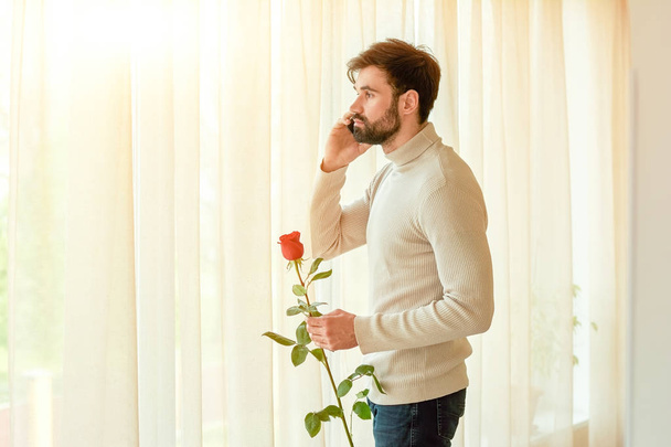 Man holding rose and phone. - Foto, imagen