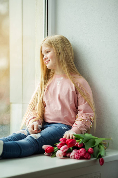 Pretty blonde girl with bouquet of tulip pink flowers. Easter concept - Φωτογραφία, εικόνα