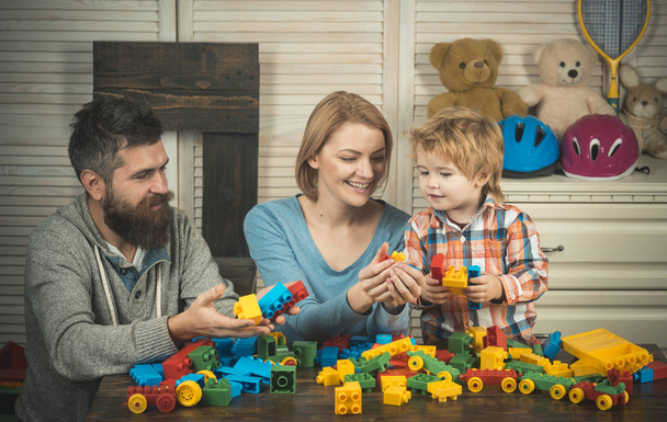 Parents and kid with happy faces hold colorful bricks. - Foto, Bild