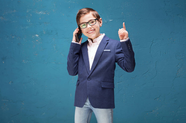 Smart boy in eyeglasses talking by mobile phone. - Zdjęcie, obraz