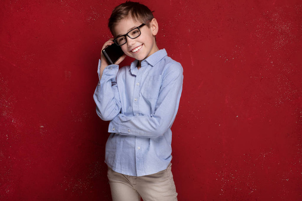 Smart boy in eyeglasses talking by mobile phone. - Photo, Image
